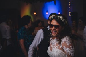 Bride having fun wearing sunglasses whilst dancing on her wedding day at River Cottage